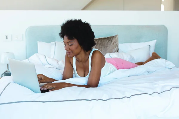 年轻的非洲裔美国女人躺在床上用笔记本电脑 抄袭空间 生活方式 家庭和技术概念不变 — 图库照片