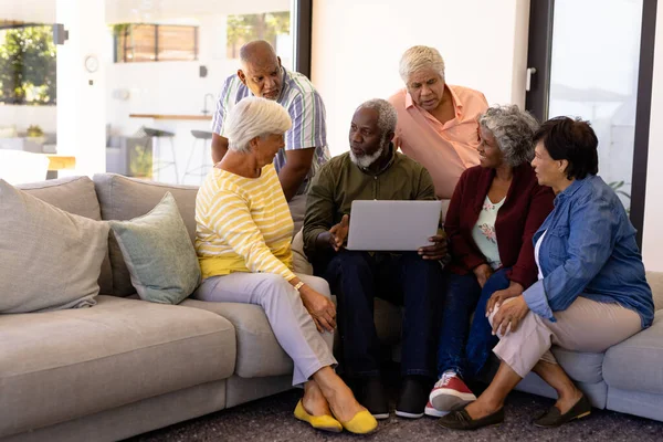 Multiracionális Idősebb Férfi Laptoppal Magyarázza Barátainak Miközben Kanapén Idősek Otthonában — Stock Fotó
