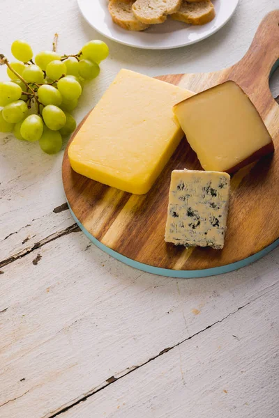 高角度的各种奶酪放在木板上 葡萄放在桌子上 复制空间 水果和奶制品 — 图库照片