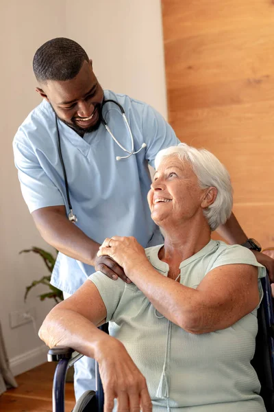 アフリカ系アメリカ人男性の健康労働者が車椅子に座っている白人のシニア女性を支援している 医療と定年退職シニアライフスタイルの概念 — ストック写真