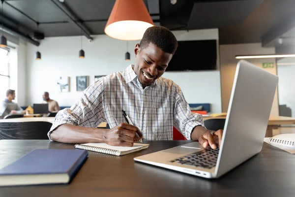 Χαμογελώντας Νεαρός Αφροαμερικανός Επιχειρηματίας Που Γράφει Στο Ημερολόγιο Και Χρησιμοποιεί — Φωτογραφία Αρχείου
