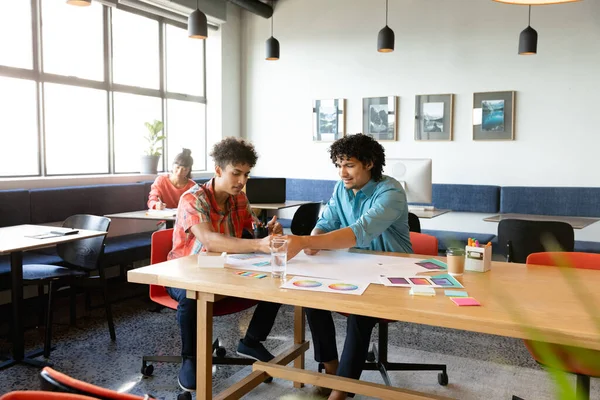 オフィスのテーブルでチャートについて議論する創造的な出生の同僚 変化のないチームワーク創造的なビジネス職場多様性デザインの職業 — ストック写真