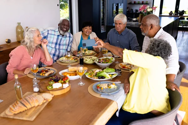 Багаторасова Старша Жінка Показує Смартфон Друзям Обідаючи Обіднім Столом Догляд — стокове фото
