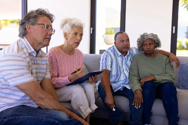 在养老院的治疗课上 多种族女性治疗师与老年人坐在沙发上 精神压力 心理治疗 辅助生活 — 图库照片