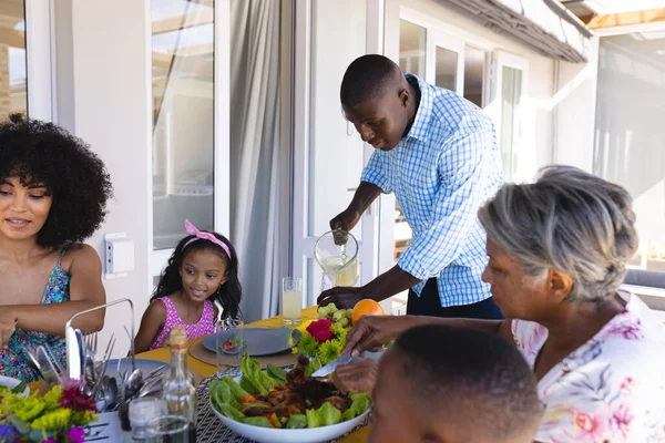 Uomo Afroamericano Che Serve Bevande Alla Famiglia Multirazziale Mentre Pranza — Foto Stock