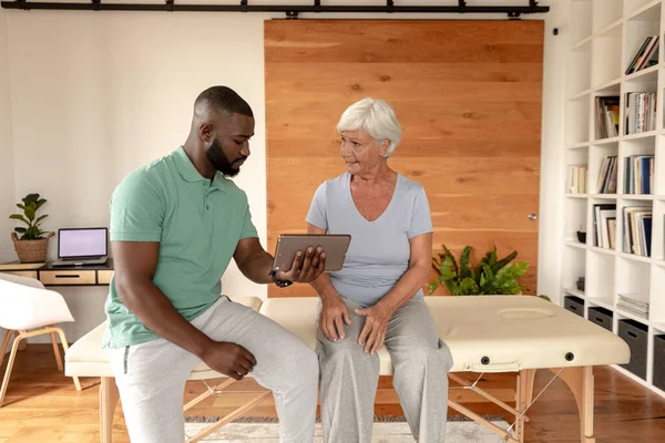 Afrikanisch Amerikanischer Physiotherapeut Mit Digitalem Tablet Diskutiert Mit Kaukasischer Seniorin — Stockfoto