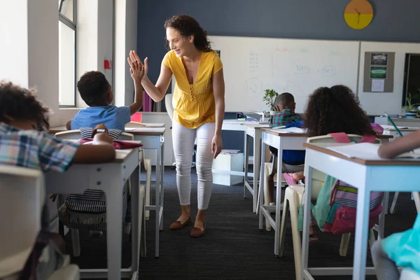 幸せな白人の若い女性教師は アフリカ系アメリカ人の少年に机の上に座って5を与えます 変化のない教育子供時代教育学習学校の概念 — ストック写真