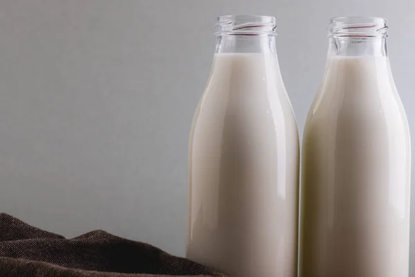 Närbild Mjölk Glasflaskor Mot Grå Bakgrund Med Kopieringsutrymme Oförändrat Mat — Stockfoto