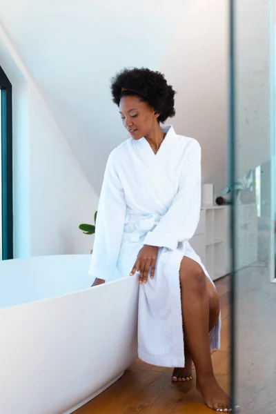 浴槽に座っている間 白いバスローブを着たアフリカ系アメリカ人の若い女性は スペースをコピーします 変更されていない リラクゼーション 甘やかす デトックス ボディケアと健康の概念 — ストック写真