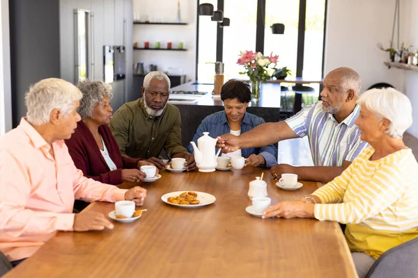 Amigos Seniores Multirraciais Tomando Café Biscoitos Enquanto Sentam Mesa Jantar — Fotografia de Stock