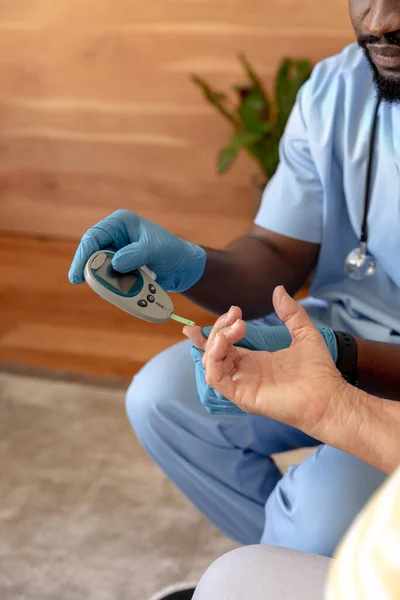 アフリカ系アメリカ人男性の健康労働者は 血糖値計を使用して白人高齢女性の血糖値を測定します 医療と定年退職シニアライフスタイルの概念 — ストック写真