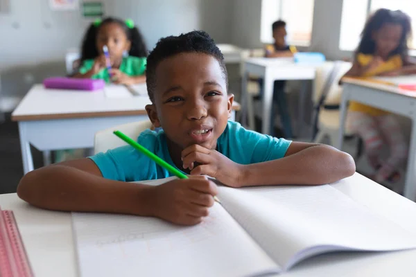 非裔美国小学生上课时坐在课桌前做鬼脸 学习和学校观念 — 图库照片