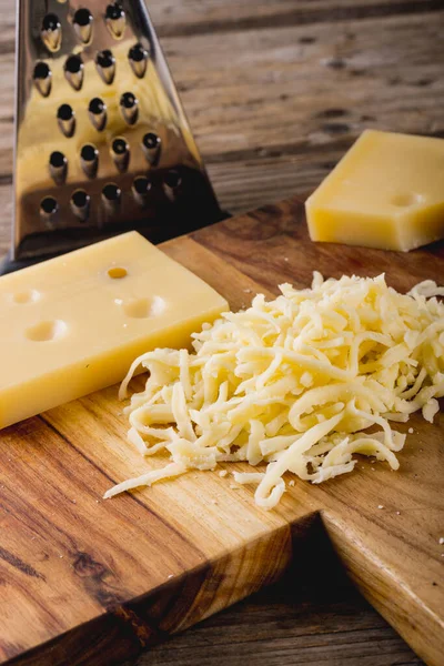 stock image Close-up of grated cheese on wooden board by grater at table, copy space. unaltered, food and dairy product.