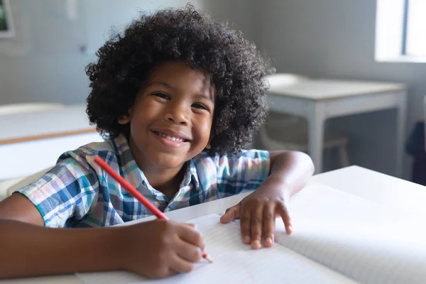 一个微笑的非洲裔美国小学生在课桌前写书的肖像 学习和学校概念 — 图库照片