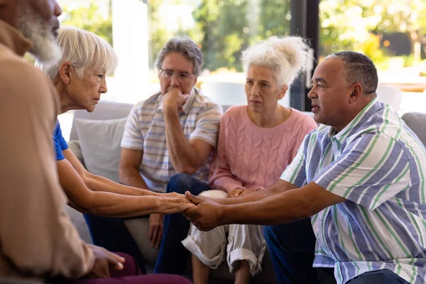 多种族老年人与朋友坐在一起进行集体治疗时手牵着手 感到安慰 感情上的压力 在一起 帮助生活 退休回家 — 图库照片
