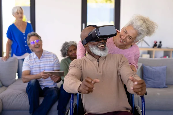 車椅子に座っている間に仮想現実シミュレータを使って友人を見ている多人種高齢者 老人ホーム 変化のない 創造的な 一緒に サポート 支援された生活 — ストック写真