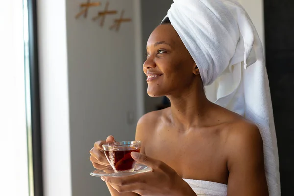 身穿浴衣的非洲裔美国妇女在家里举着茶杯微笑 自我照顾 卫生和放松的概念 — 图库照片
