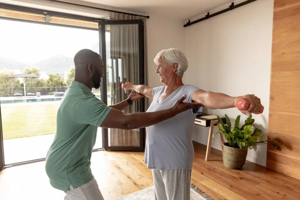 Afrika Kökenli Amerikalı Erkek Fizyoterapist Beyaz Yaşlı Kadının Halterlerle Egzersiz — Stok fotoğraf
