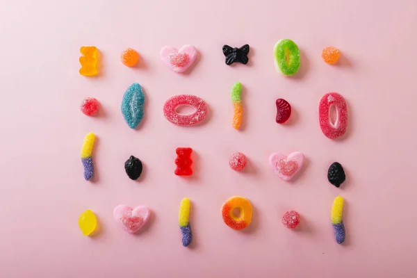 ピンクの背景に配置された異なる形の複数の色の砂糖菓子のビューの真上 変化のない不健康な食生活と甘い食の概念 — ストック写真