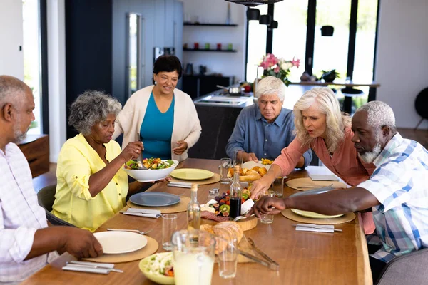 多种族的老朋友在疗养院的饭桌上吃午饭 辅助生活和退休概念 — 图库照片