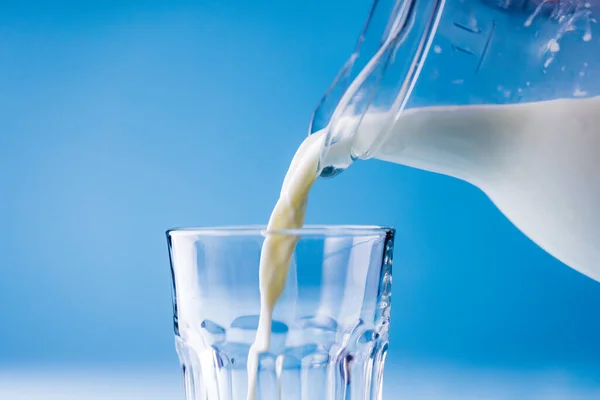 将牛奶从玻璃瓶中倒入蓝色背景的特写 复制空间 摄影棚拍摄和健康食品概念 — 图库照片