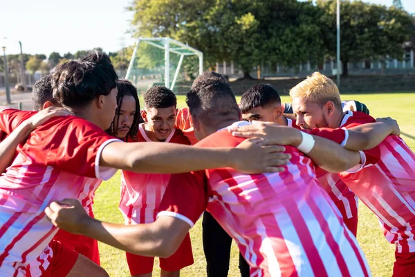 Multiraciale Mannelijke Team Spelers Rode Uniformen Knuffelen Bespreken Speelplaats Tijdens — Stockfoto