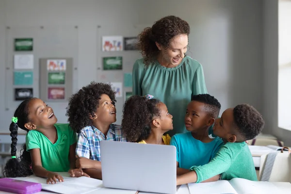 笑顔の白人の若い女性教師アフリカ系アメリカ人の小学生にラップトップを教える 変化のない教育子供時代教育学習無線技術学校の概念 — ストック写真
