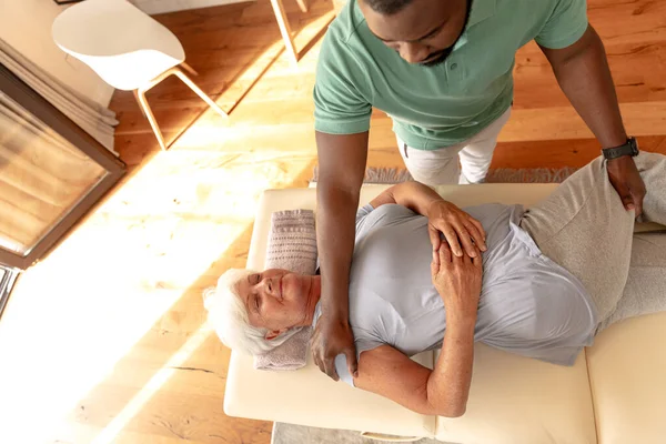 Afrikanische Amerikanische Männliche Physiotherapeutin Die Kaukasische Seniorin Hause Massiert Physiotherapie — Stockfoto