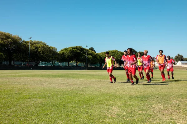 Equipe Futebol Masculino Multirracial Vestindo Uniformes Vermelhos Correndo Terra Gramada — Fotografia de Stock