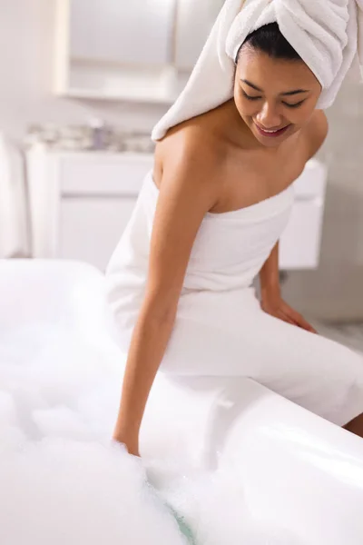 バスルームでは コピースペースと泡風呂を準備し タオルを身に着けている笑顔の出産の女性の垂直 リラクゼーション セルフケア 美しさ レジャー ライフスタイルのコンセプト — ストック写真