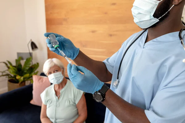 アフリカ系アメリカ人男性の健康労働者の中央部は 自宅のベールボトルから注射器を埋めます 医療と定年退職シニアライフスタイルの概念 — ストック写真