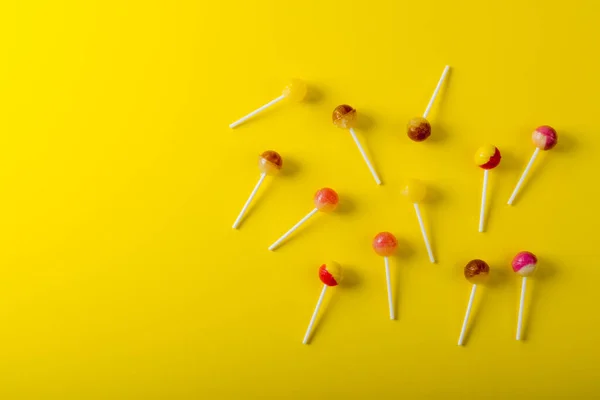 黄色の背景にコピースペースによって散乱ロリポップのオーバーヘッドビュー 変化のない不健康な食生活と甘い食の概念 — ストック写真