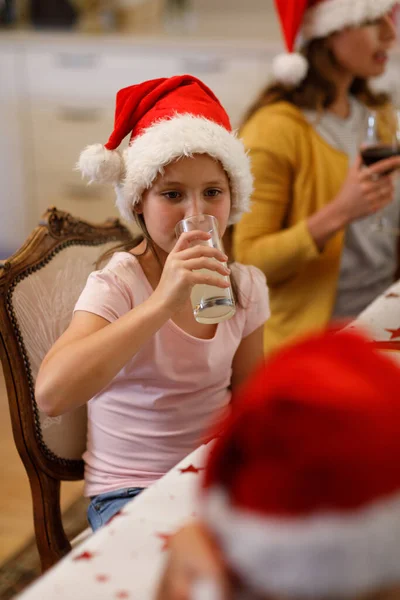 Menina Branca Sentada Mesa Bebendo Suco Usando Chapéu Papai Noel — Fotografia de Stock