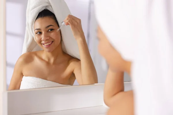 Biracial Woman Wearing Towel Smiling Bathroom Mirror Holding Essential Oil — Stock Photo, Image