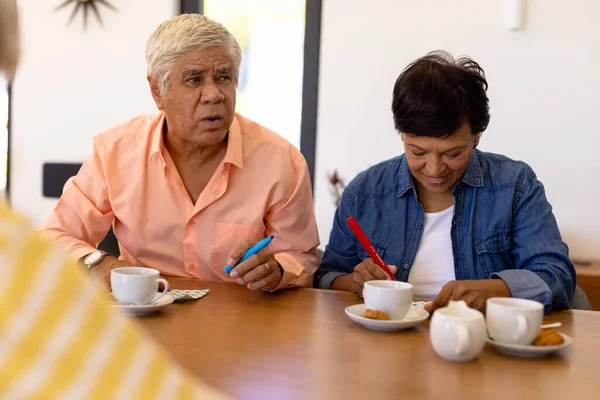 Amigos Mayores Birraciales Jugando Bingo Mientras Toman Café Galletas Mesa —  Fotos de Stock