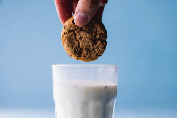 Coupé Main Personne Trempant Cookie Dans Lait Sur Fond Bleu — Photo