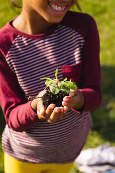 Środek Birasowej Uśmiechniętej Dziewczyny Trzymającej Kompost Sadzonkę Stojąc Podwórku Ogrodnictwo — Zdjęcie stockowe