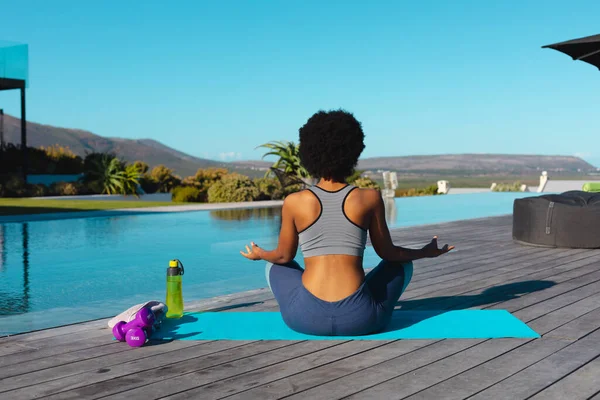 プールの近くでヨガや瞑想を練習しているアフリカ系アメリカ人女性の背面図 フィットネスと健康的なライフスタイルのコンセプトF — ストック写真