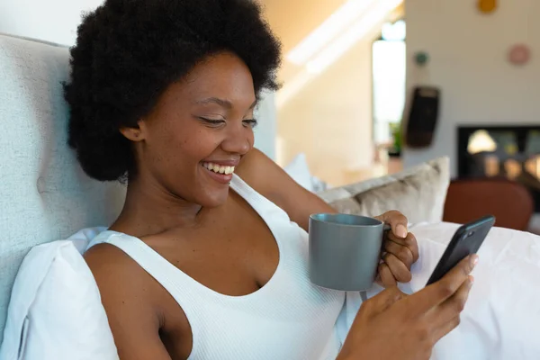 Весела Афроамериканська Молода Жінка Яка Має Каву Використовуючи Смартфон Спальні — стокове фото