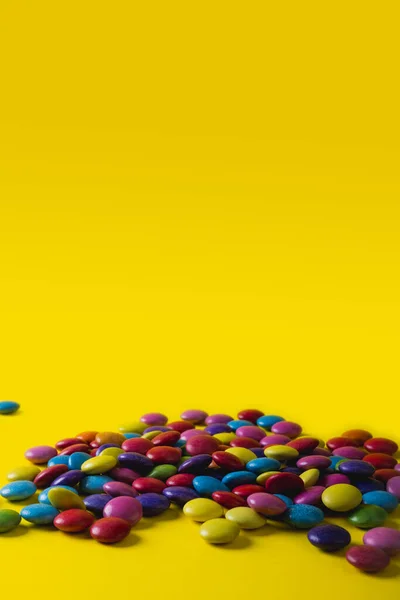 Sarı Arka Planda Fotokopi Alanı Olan Renkli Çikolata Şekerleri Yığını — Stok fotoğraf