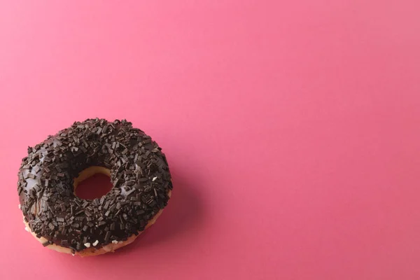 巧克力洒水器的新鲜甜甜圈的高角度视图 通过复制空间粉红色背景 不变的 不健康的饮食和甜食概念 — 图库照片