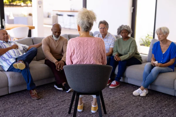 在养老院 多种族女性治疗师与老年人坐在沙发上进行集体治疗 心理治疗 辅助生活 — 图库照片