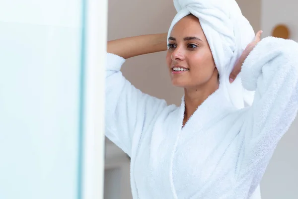 穿着浴衣的白人女人看着镜子里的家 自我照顾 卫生和放松的概念 — 图库照片