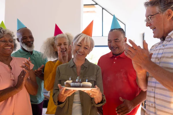 多种族朋友鼓掌歌唱 为快乐的老年妇女举行生日杯蛋糕 疗养院 辅助生活和退休概念 — 图库照片