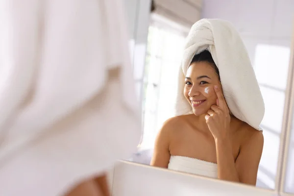 Mulher Biracial Feliz Usando Toalha Sorrindo Espelho Banheiro Rosto Hidratante — Fotografia de Stock