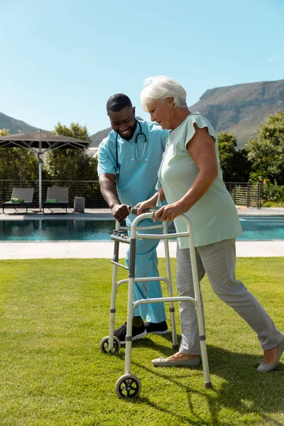 Afrikkalainen Amerikkalainen Mies Terveydenhuollon Työntekijä Auttaa Valkoihoinen Vanhempi Nainen Kävellä — kuvapankkivalokuva