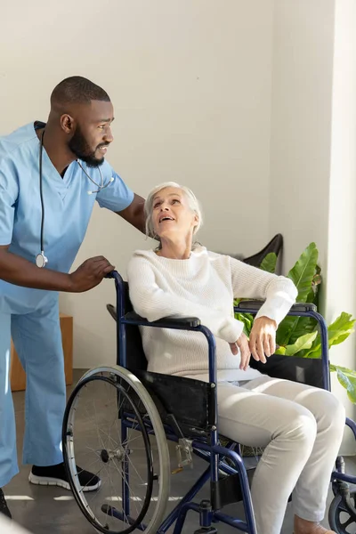 非洲裔美国医生站在坐在轮椅上的白人老年妇女身边 复制空间 未经改动 医疗保健 身体损伤 康复和残疾 — 图库照片