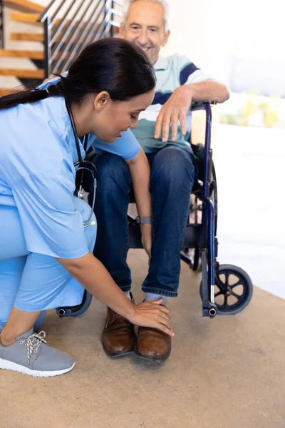 Γεννητική Φυσιοθεραπεύτρια Προσαρμόζει Πόδια Ενός Καυκάσιου Ηλικιωμένου Που Κάθεται Αναπηρική — Φωτογραφία Αρχείου