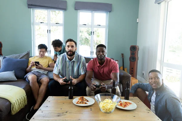 多种族男性朋友 家里有啤酒瓶 桌上有食物 在沙发上玩电子游戏 复制空间 享受及周末活动概念 — 图库照片