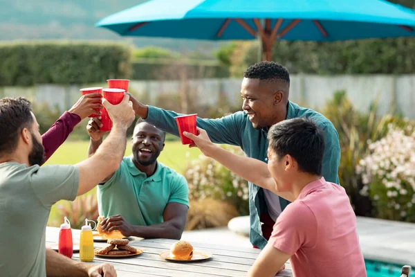 Felices Amigos Masculinos Multirraciales Con Comida Mesa Brindando Bebidas Mientras —  Fotos de Stock